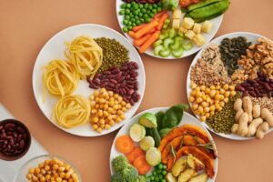 A vibrant mix of legumes, vegetables, nuts, and pasta arranged on white plates showcasing a balanced, healthy diet packed with vitamin b1 thiamine.